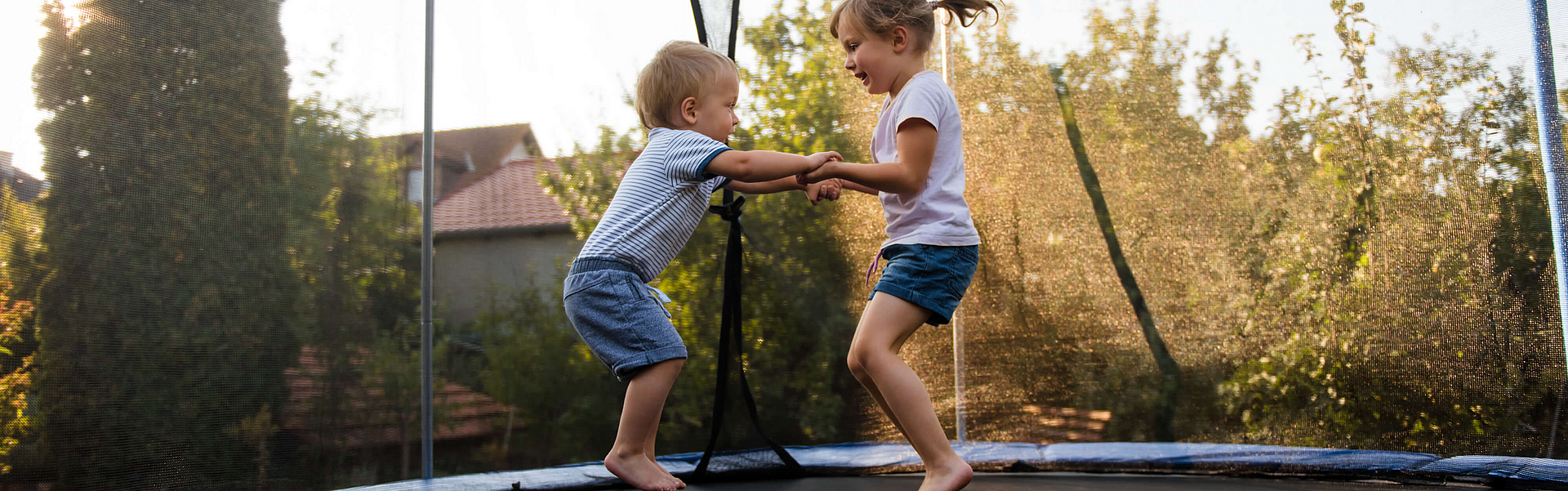 Geschwister amüsieren sich beim Springen auf Trampolin.