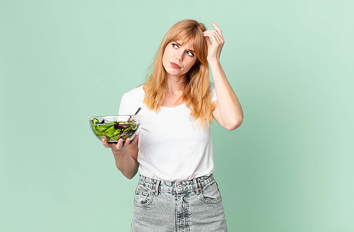 Nachdenkliche Frau mit Salat in der Hand