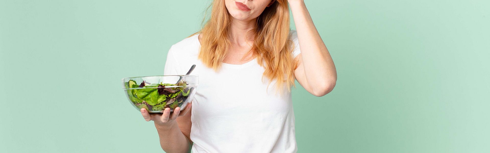 Nachdenkliche Frau mit Salat in der Hand
