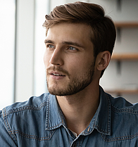 Mann schaut nachdenklich aus dem Fenster. Er überlegt ob er sich aufgrund seiner Erkrankung für eine moderne Therapie entscheidet.