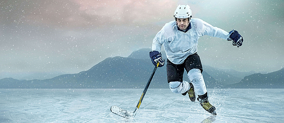 Ein Eishockeyspieler sprintet einem Puk hinterher. Sein Schläger ist auf dem Eis.