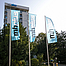 Foto der mhplus-Hauptzentrale in Ludwigsburg: Büro-Hochhaus in der Sonne mit Bäumen und drei Fahnen davor