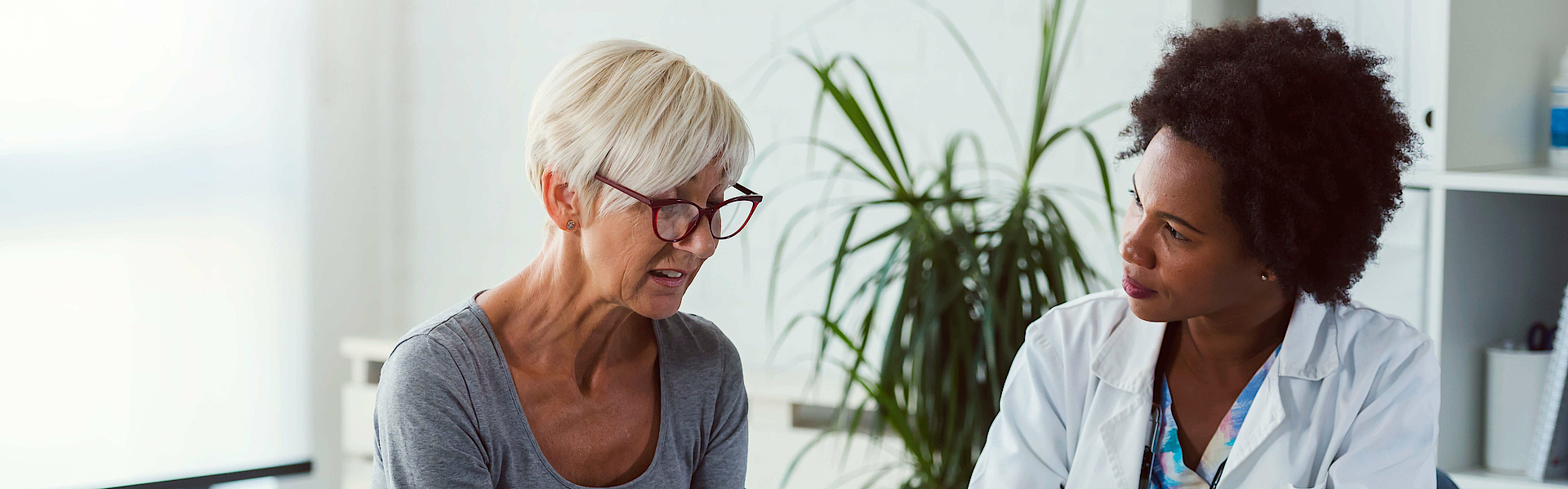 Eine Ärztin und eine Patientin sitzen sich gegenüber. Die Ärztin spricht mit der Patientin und berät sie.