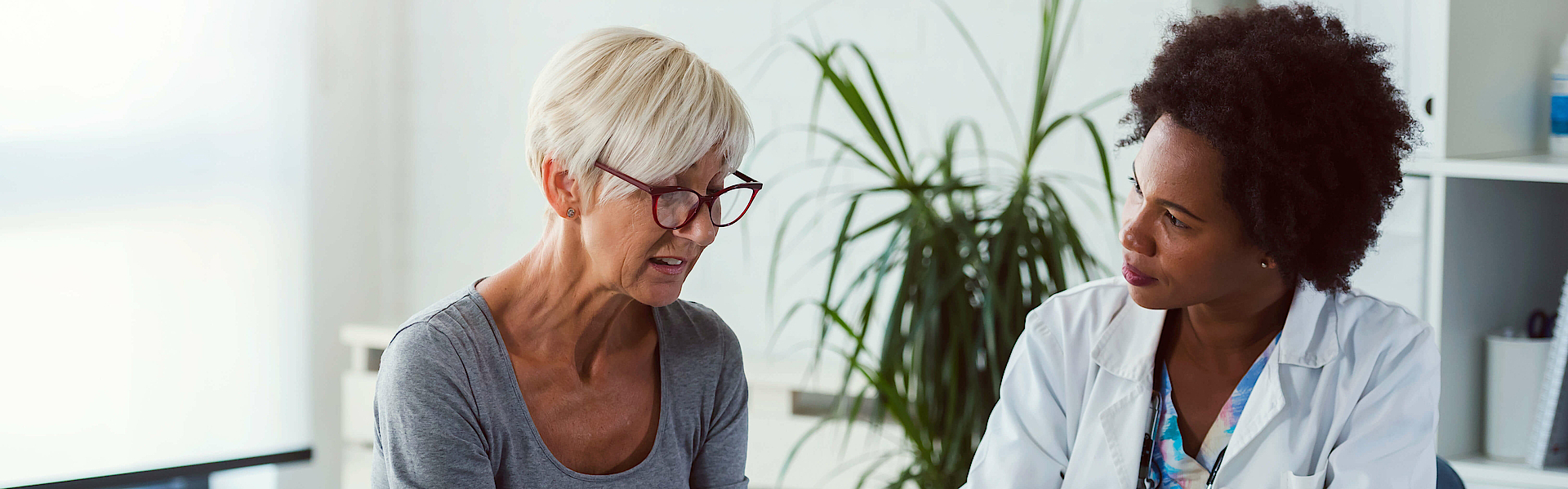 Eine Ärztin und eine Patientin sitzen sich gegenüber. Die Ärztin spricht mit der Patientin und berät sie.