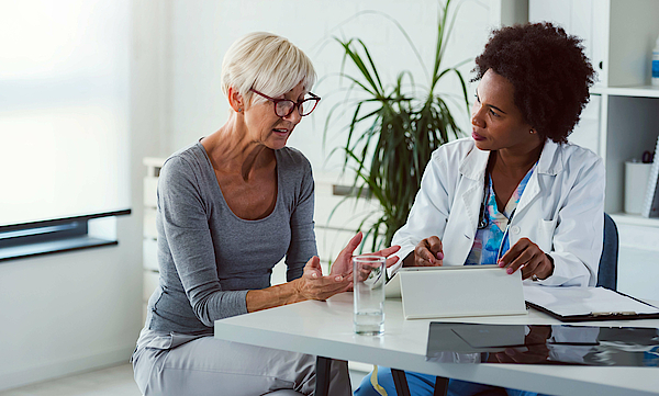 Eine Ärztin und eine Patientin sitzen sich gegenüber. Die Ärztin spricht mit der Patientin und berät sie.