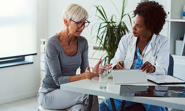 Eine Ärztin und eine Patientin sitzen sich gegenüber. Die Ärztin spricht mit der Patientin und berät sie.