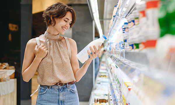 Zu sehen ist eine Frau, die Milch in der Hand hält.