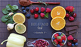Flavonoid-Reiches Essen liegt in Form eines Vierecks auf einem dunklen Holz-Untergrund. In der Mittel liegt eine kleine Tafel mit der Aufschrift "BIOFLAVONOID food ~vitamin P~".
