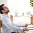 Ein Mann sitzt an einem Tisch. Er arbeitet im Homeoffic. Er ist gestresst und nimmt sich einige Minuten Zeit Luft zuholen.