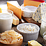 Calciumhaltige Lebensmittel wie verschiedene Käsesorten und Milch stehen auf einem Tisch