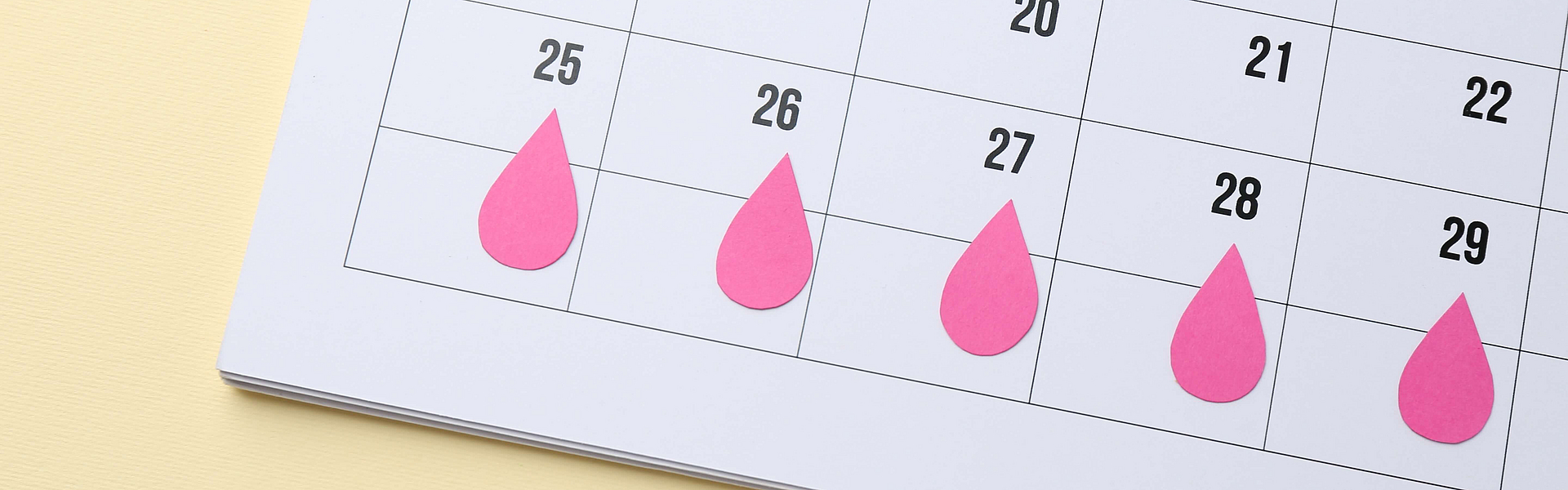 In einem Kaender sind die Tage der Periode mit roten Tropfen gekennzeichnet
