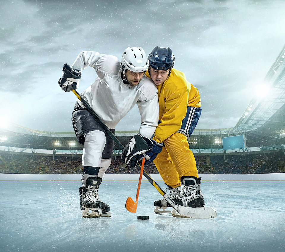 Zwei Eishockeyspieler stehen sich gegenüber. Einer trät ein weißes Trikot, der andere ein gelbes. Sie stehen am Abschlag. Die Schläger sind gesenkt. Sie möchten das Spiel beginnen.