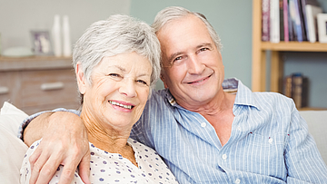 Porträt von Senioren, die zu Hause auf dem Sofa sitzen