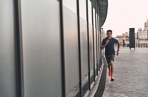 Mann joggt in der Stadt, entlang einer Wand