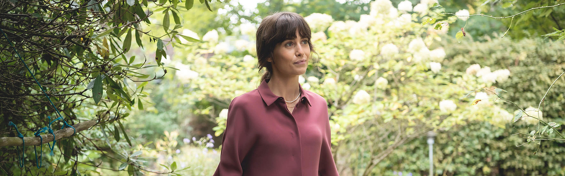 Frau mit einem Korb voller Gemüse steht im Garten.