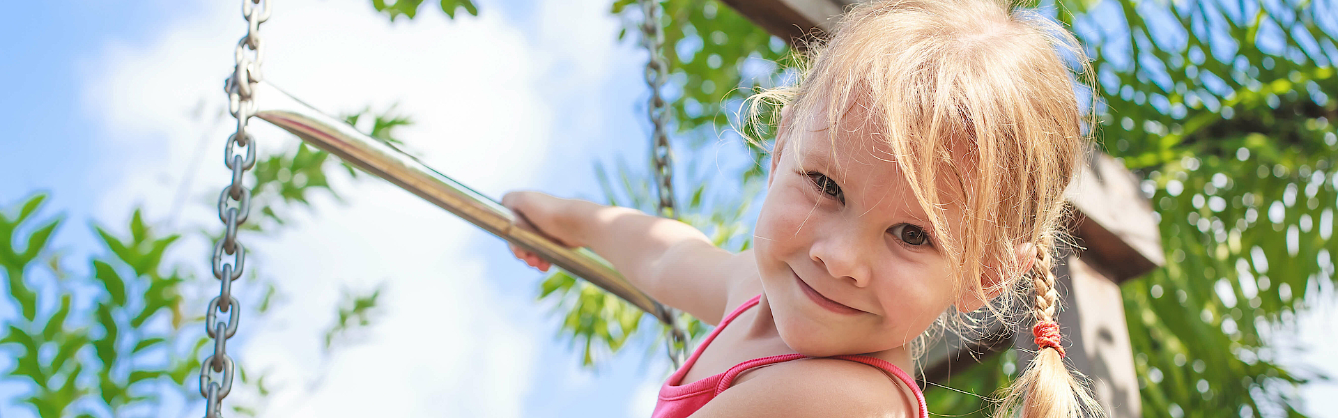 Mädchen ist auf einem Spielplatz und klettert an einem Klettergerüst.