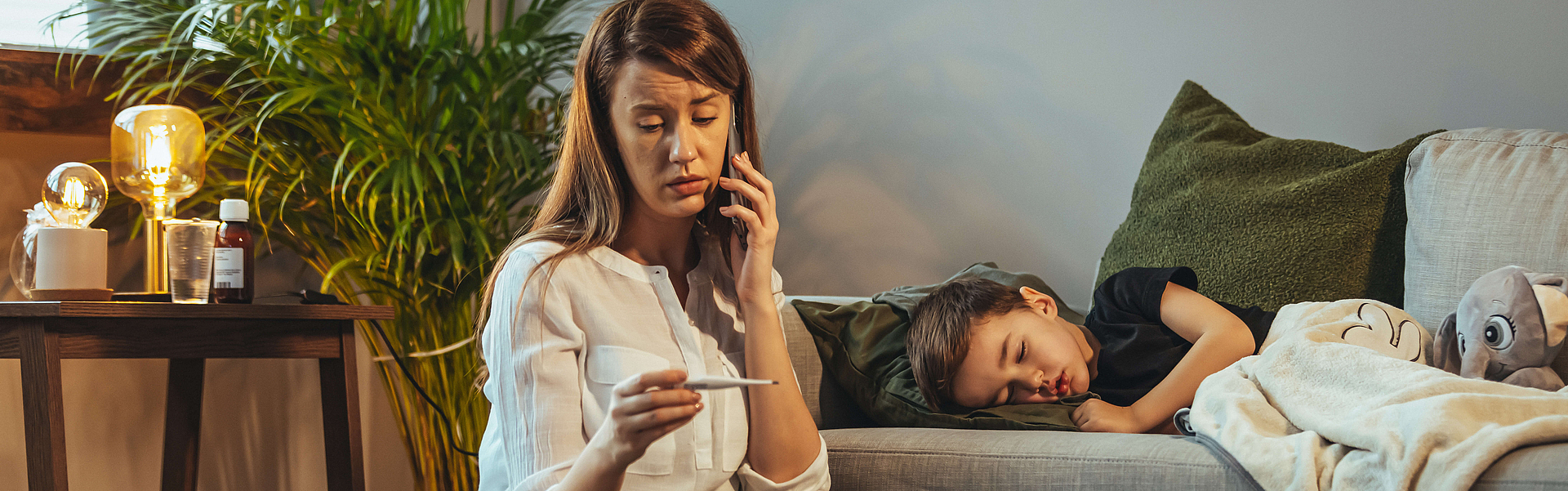 Schuss von einer Mutter, die zu Hause einen Anruf macht, während sie ihrem kranken jungen Sohn hilft. Mutter überprüft die Temperatur ihres kranken Sohnes. Nahaufnahme einer Mutter, die die Temperatur ihres Jungen überprüft.