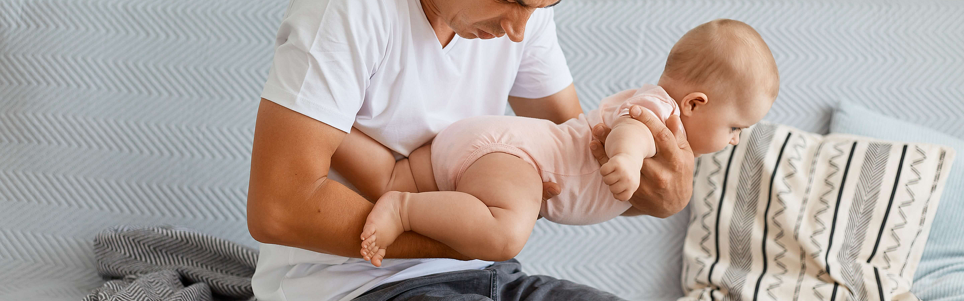 Ein Vater riech am Po seines Babys, dass vielleicht Durchfall hat.