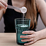Frau löst Kreatin in einem Glas Wasser auf. 