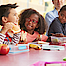 Eine Gruppe Schulkinder sitzt beisammen. Sie essen ihr Pausenbrot.