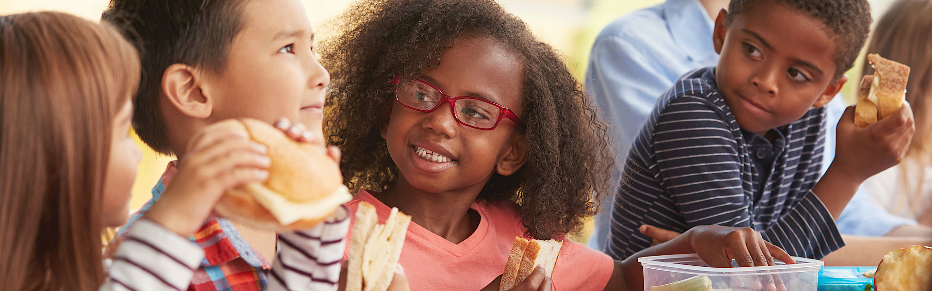 Eine Gruppe Schulkinder sitzt beisammen. Sie essen ihr Pausenbrot.