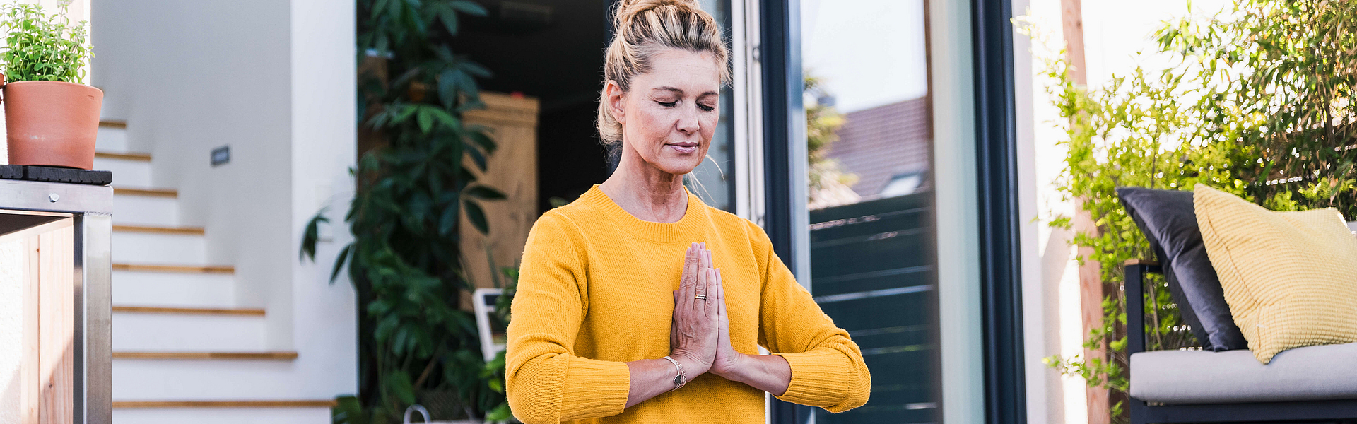 Frau auf einer Terasse übt eine Yoga-Position