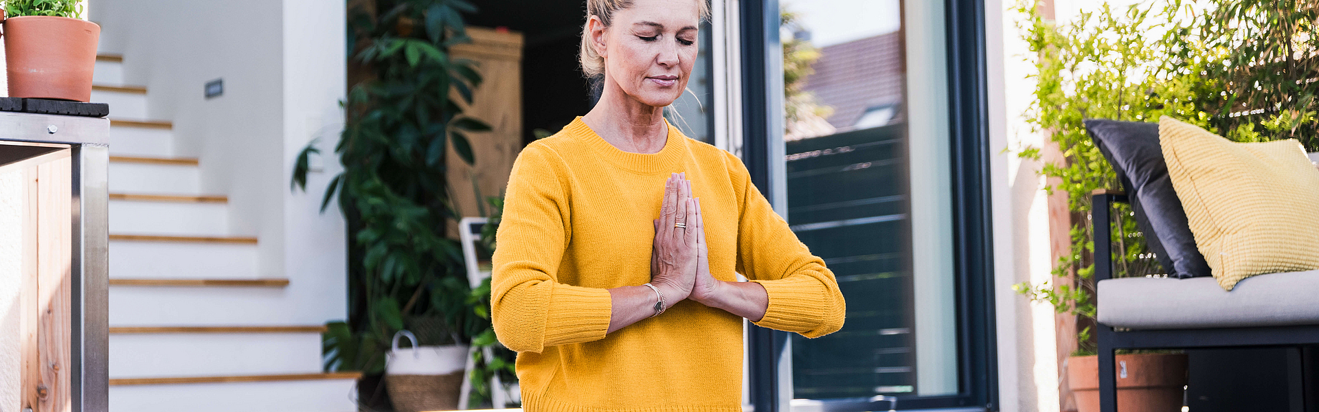 Frau auf einer Terasse übt eine Yoga-Position