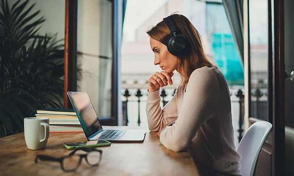 Zu sehen ist eine Frau, die mit dem Laptop arbeitet.