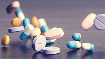 Tabletten auf dunklem Hintergrund, die herunterfallen. 