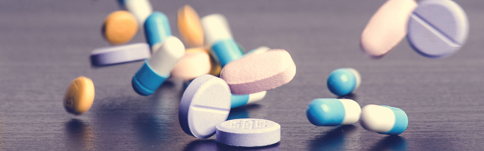 Tabletten auf dunklem Hintergrund, die herunterfallen. 