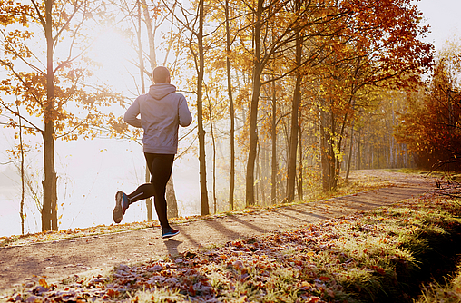 Mann joggt im Winter im Wald.