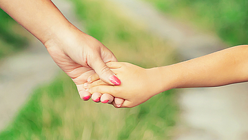 Händchenhalten mit der Mutter gibt dem Kind Sicherheit. Mit der Sozialmedizinische Nachsorge unterstützt die mhplus schwer kranke Kinder.