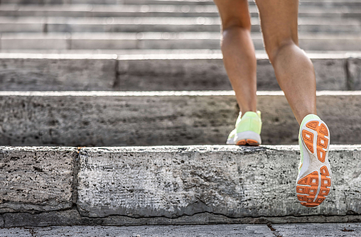 Beine in Laufschuhen auf einer Treppe.