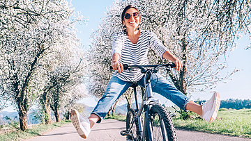 Frau fährt mit dem Fahrrad und hat die Beine weit von den Pedalen weggestreckt.