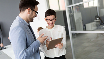 Mann und Frau besprechen sich anhand der Notizen im Tablett.