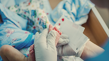 Bei einem Baby wird für eine Untersuchung Blut vom Fuß genommen.