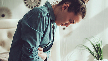 Zu sehen ist eine Frau mit Bauchschmerzen.