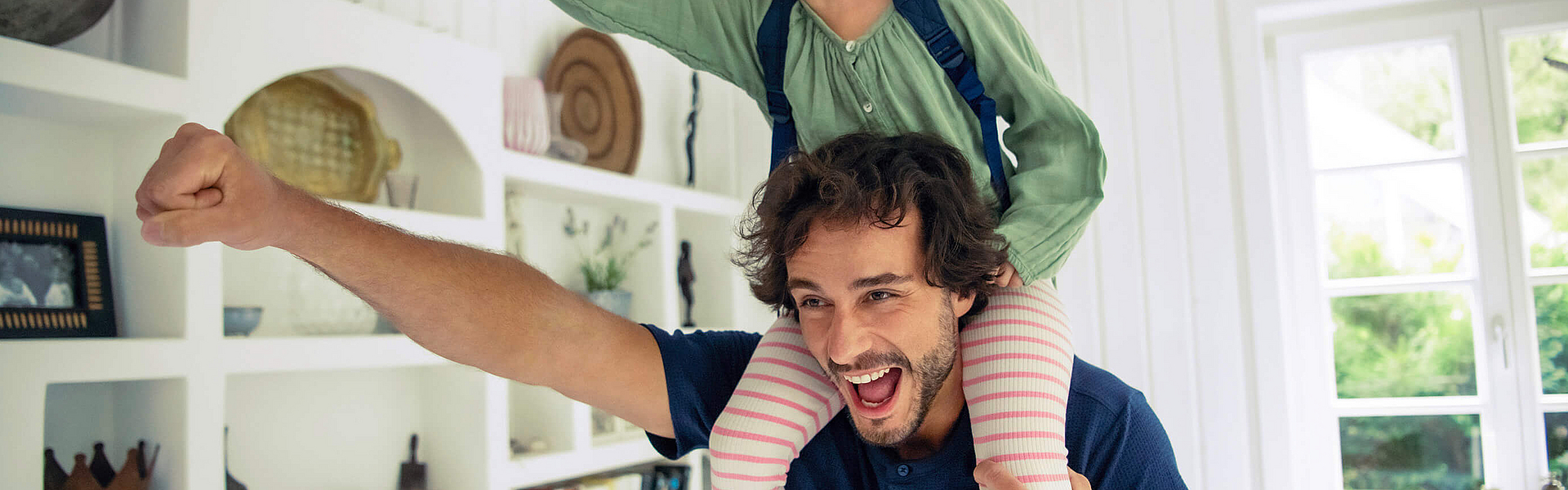 Vater trägt seine Tochter huckepack, beide strecken einen Arm mit einer Faust nach vorne.