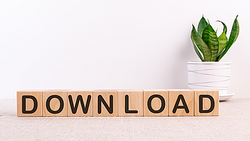 Würfel aus Holz bilden das Wort Download. Sie sind vor einer Pflanze angeordnet.