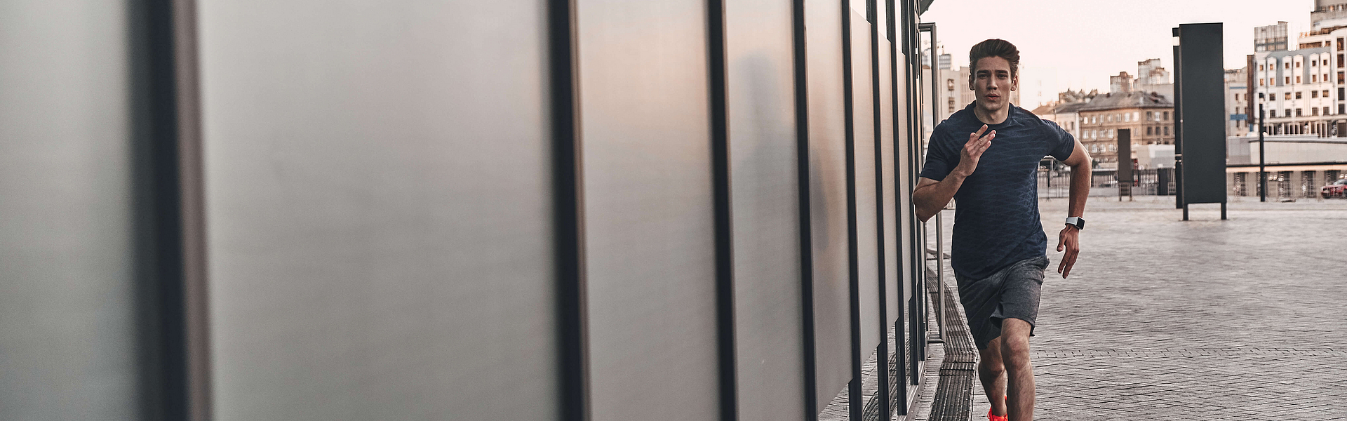 Mann joggt in der Stadt, entlang einer Wand