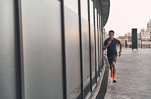 Mann joggt in der Stadt, entlang einer Wand