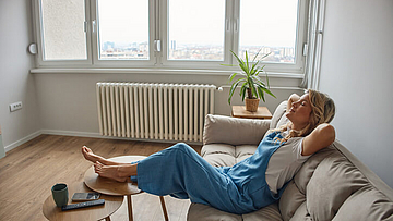 Frau liegt entspannt auf einem Sofa