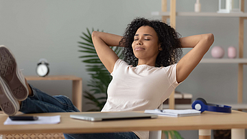 Junge Frau, sitzt entspannt am Schreibtisch.