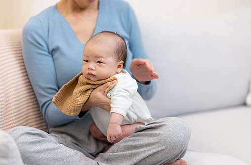 Eine Mutter klopft ihrem Neugeborenen wegen Schluckauf auf den Rücken