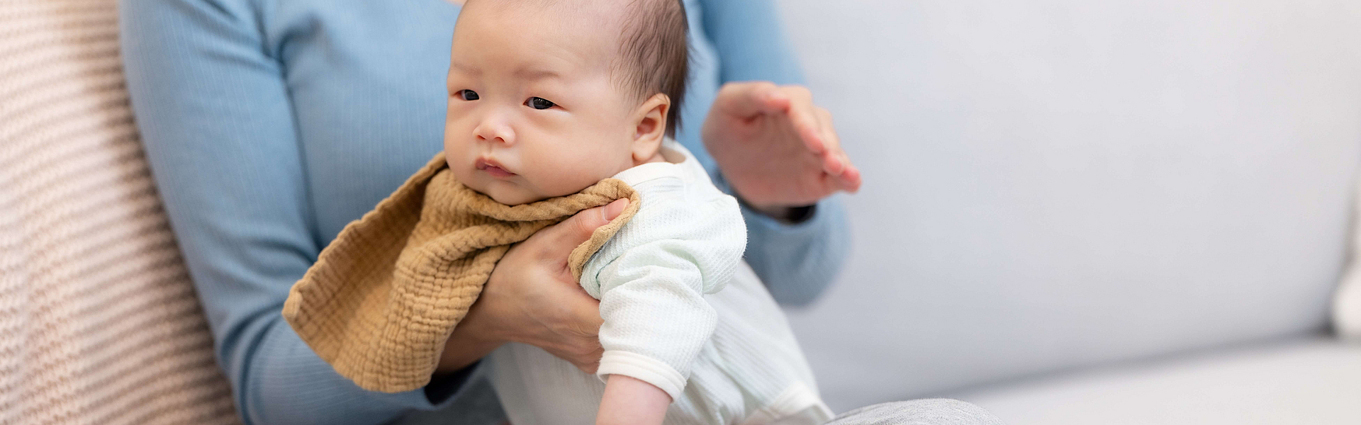 Eine Mutter klopft ihrem Neugeborenen wegen Schluckauf auf den Rücken