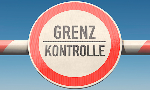 Schranke an einer Grenze mit der Aufschrift Grenze und Kontrolle