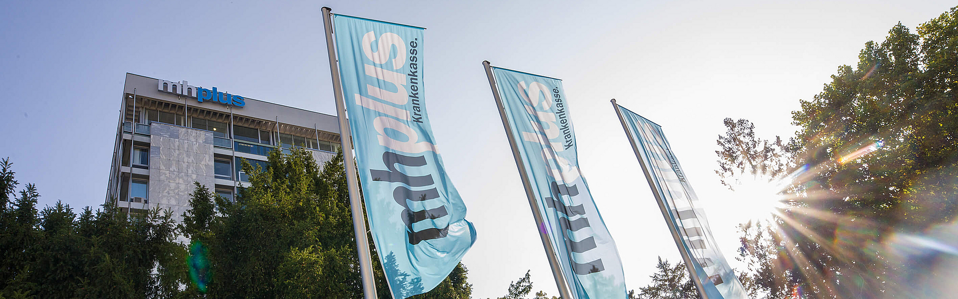 Das Bürogebäude und Hauptsitz der mhplus Krankenkasse in Ludwigsburg mit Flaggen und Bäumen davor