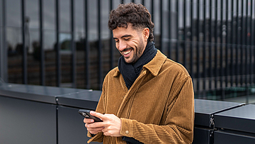 Junger Mann mit Handy in der Hand - mhplus Newsletter