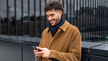 Junger Mann mit Handy in der Hand - mhplus Newsletter