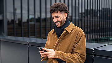 Junger Mann mit Handy in der Hand - mhplus Newsletter